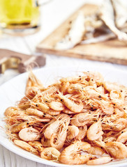 Boiled shrimp on white plate, beer mug behind