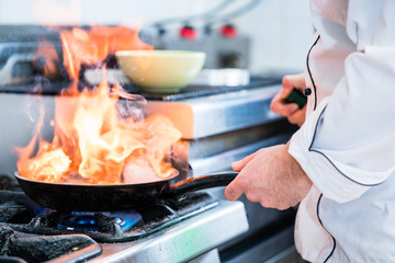 Chef doing flambe to dish in pan