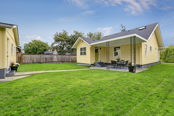 Fototapeta na wymiar Green grass filled backyard area of American yellow house.