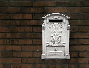 mailbox metal painted in white on a background of red bricks