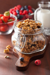 homemade healthy granola in glass jar and berries