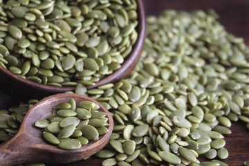 Pumpkin seeds in wooden bowl with wooden spoon
