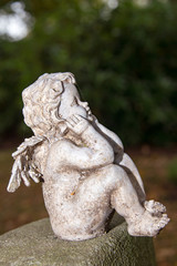 Engel hockt auf einem Grabstein