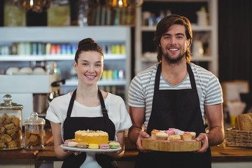 Portrait of waiter and waitress holding a tray of cupcakes