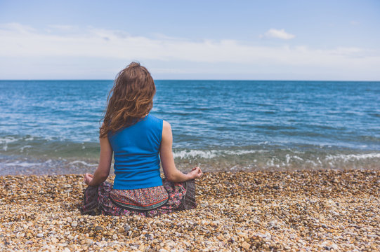 Young woman meditating on the beach