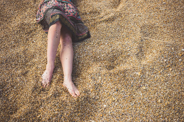 Legs of a young woman on pebble beach