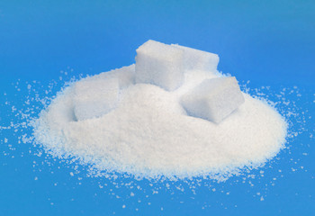 Pile of white sugar isolated on blue background