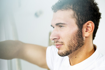 Obraz premium Young handsome man. Pretty young guy looking throw window. Close up. Profile. 