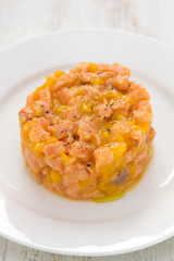 salmon with mango on white plate on white wooden background