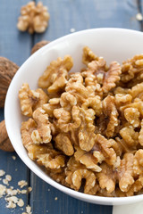 walnut in white bowl on blue wooden background