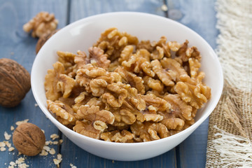 walnut in white bowl on blue wooden background