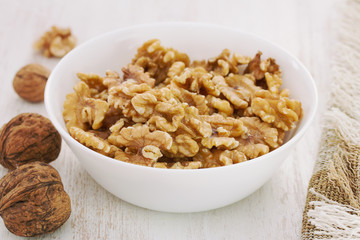 walnut in white bowl on white wooden background