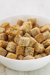 dry bread in white bowl on white wooden background
