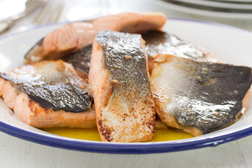 fried salmon on white dish on wooden background