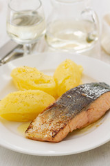 fried salmon with potato on white dish on wooden background
