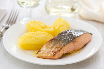 fried salmon with mashed potato on white dish on wooden background