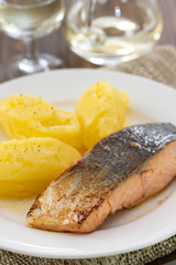 fried salmon with mashed potato on white dish on brown wooden background