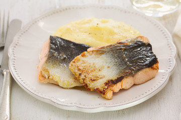 fried salmon with mashed potato on white dish on white wooden background