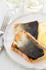 fried salmon with mashed potato on white dish on white wooden background