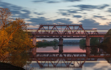 Railway bridge over the river at sunset 