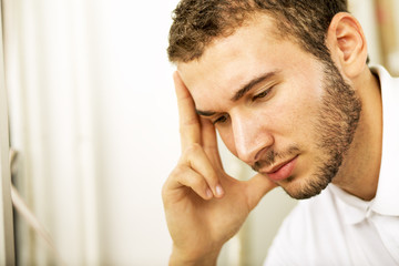 Obraz premium Young handsome man. Pretty young guy looking throw window. Close up. Profile. 