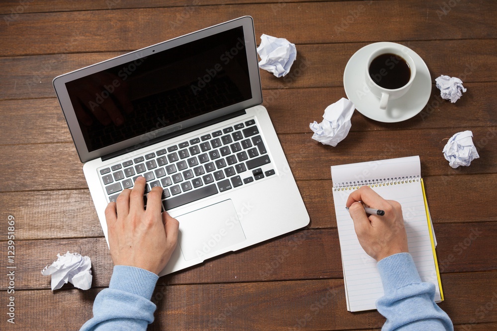Poster Man using laptop while writing on notepad