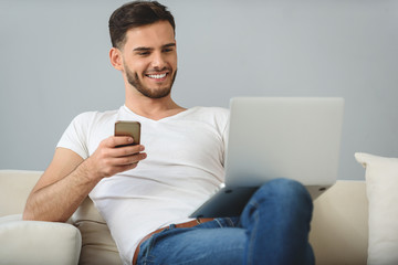 man resting on a bed with phone and notebook
