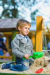 happy little boy playing in sandbox at playground