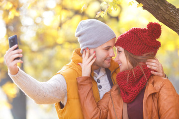 Obraz premium Portrait of young couple in park enjoying together and making selfie.
