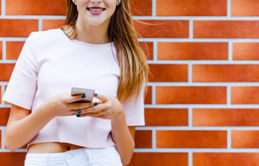 Close up Young girl texting sms on brick wall background