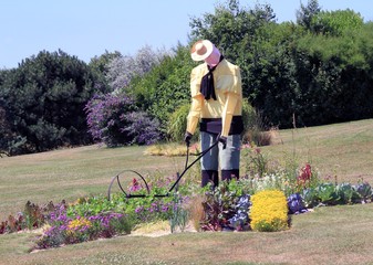 Gärtnerfigur im Blumenbeet im Park