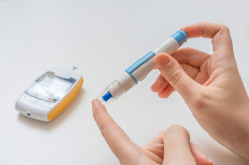 Diabetic patient is using needle and glucometer to check blood glucode level.