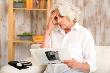 Frustrated mature lady reads paper