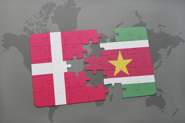 puzzle with the national flag of denmark and suriname on a world map background.