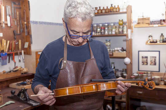 portrait of mature violin maker while testing the violins in his