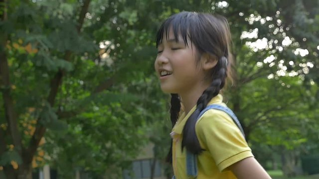 Slow motion shot : Happy Asian little girl singing and dancing in the park