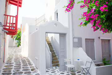 The narrow streets with blue balconies, stairs, white houses and flowers in beautiful village in Greece. Beautiful architecture building exterior with cycladic style in Mykonos
