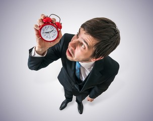 Deadline concept. Young stressed man is looking at clock and have to hurry up. View from top.