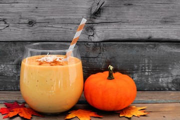 Pumpkin smoothie with coconut and cinnamon, scene on a rustic wooden background