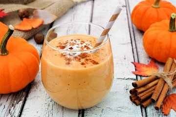 Autumn pumpkin smoothie with coconut and cinnamon, still life on white wood