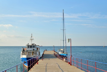 Obraz premium Pleasure boat moored to a stone pier on the sea