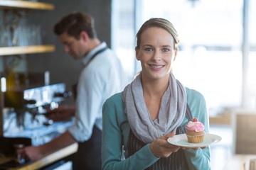 Portrait of waitress holding a plate of cupcake