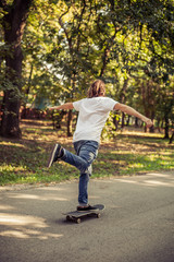 Skateboarder riding a skateboard slope on the road through the forest. Freeride skating