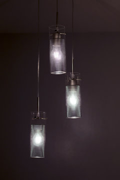 Chandelier made of glass and metal, it is hanging ceiling light. Lamp lights in the dark, room interior. 