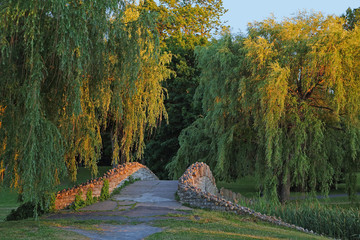 Onondaga Park Syracuse-Weeping willows framing a sun-kissed stone bridge in Syracuse NY