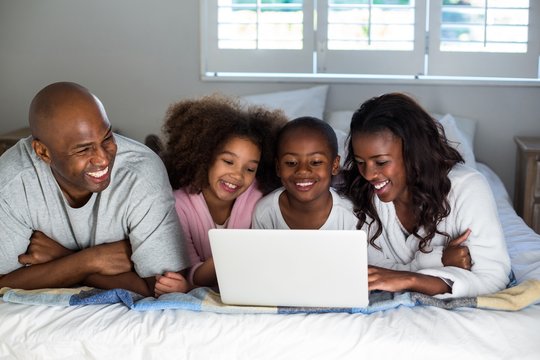 Family using laptop on bed