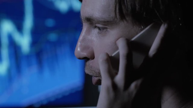 Stressed businessman working overtime late at night in the living room with telephone, computer.