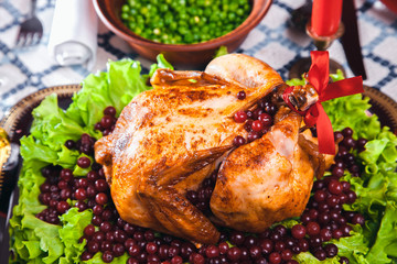 Roasted chicken, table setting. Thanksgiving table served with baked turkey, decorated with lettuce and pomegranate seeds. Christmas dinner by candlelight