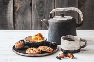 Old ceramic teapot with a Cup of tea and biscuits in a bowl on wooden background