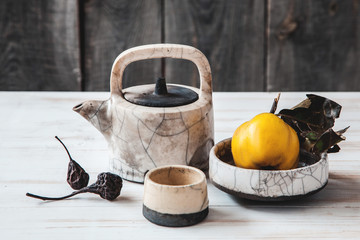 Old ceramic kettle with quinces and dried pears on wooden background